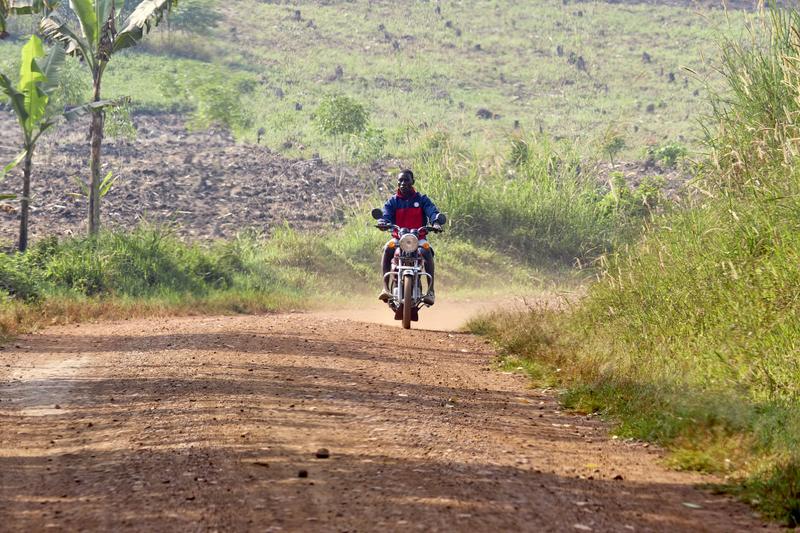 Person riding a motorcycle on a dirt road, Uganda