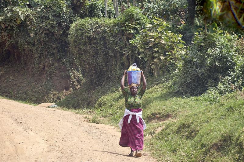 Woman walking along the street carrying a bundle on their head, Uganda