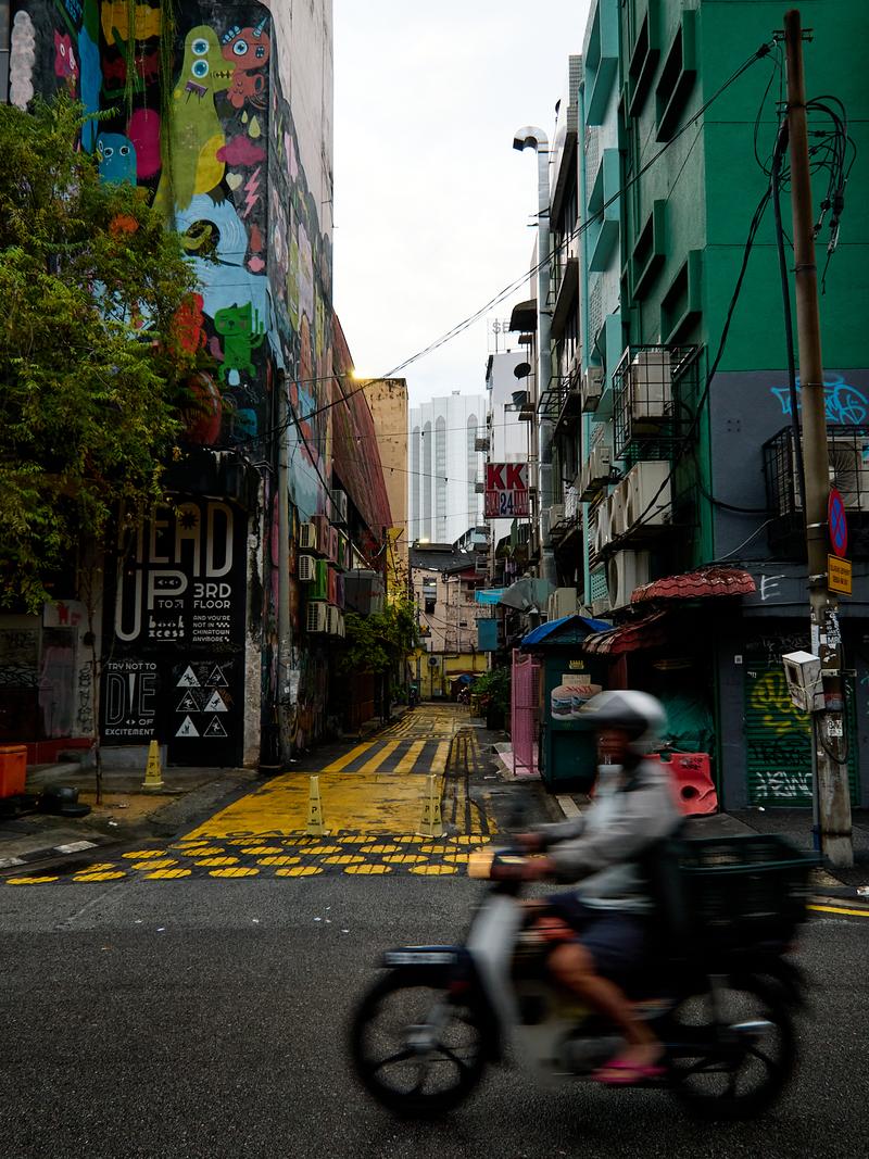 City views, colorful street art and buildings, motorcycle rider in foreground, Kuala Lumpur, Malaysia