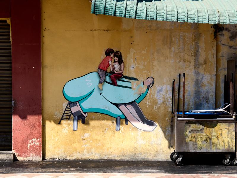 Boy and girl in a dog head slide street art, Penang, Malaysia